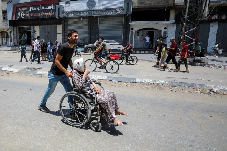 A Palestinian woman is pushed in a wheelchair as she flees her home following an Israeli military operation in Shujayea, in Gaza City [Dawoud Abu Alkas/Reuters]