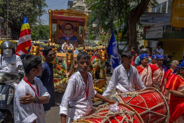 People beat drums in front of a vehicle carrying a large garlanded portrait of Bhimrao Ramji Ambedkar, the chief architect of the Indian Constitution, as they celebrate his birth anniversary in Mumbai, India, Sunday, April 14, 2024. Ambedkar, a Dalit, and a prominent Indian freedom fighter, outlawed discrimination based on caste. (AP Photo/Rafiq Maqbool)