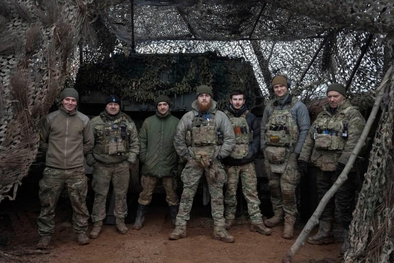 Soldiers from the Azov brigade posing for a picture in January 2024. They are standing in front of a self-propelled gun near the front line. They are in combat fatigues.