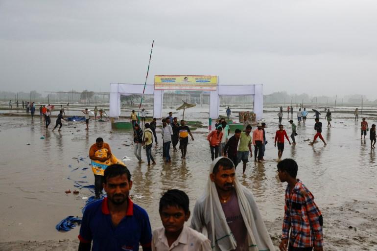 People walk on a field, where believers had gathered for a Hindu religious congregation following which a stampede occurred, in Hathras district of the northern state of Uttar Pradesh