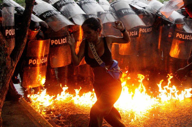 A demonstrator reacts when Molotov cocktails hit the ground in front of security forces